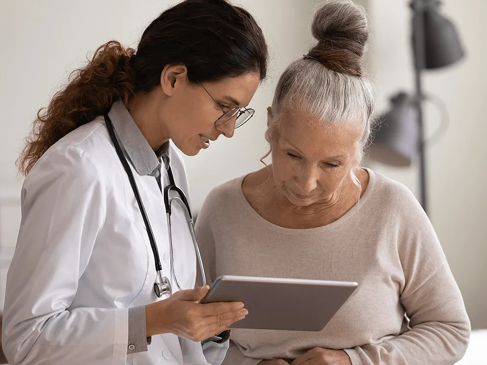 Ärztin mit älterer Patientin am Tablet