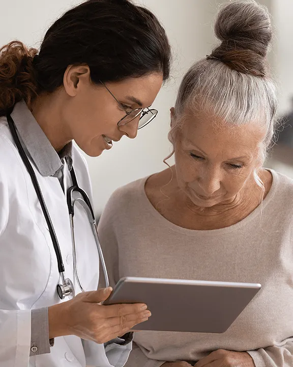 Ärztin mit älterer Patientin am Tablet